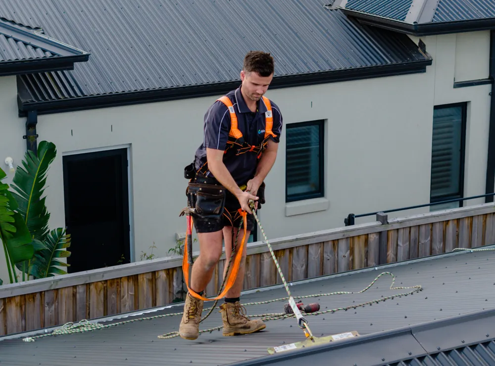 Roof plumber clipping his harness to a roof anchor