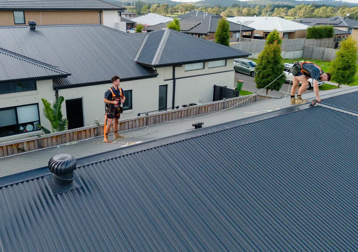 Two LifeProof roof plumbers in harnesses fixing a new Colorbond roof
