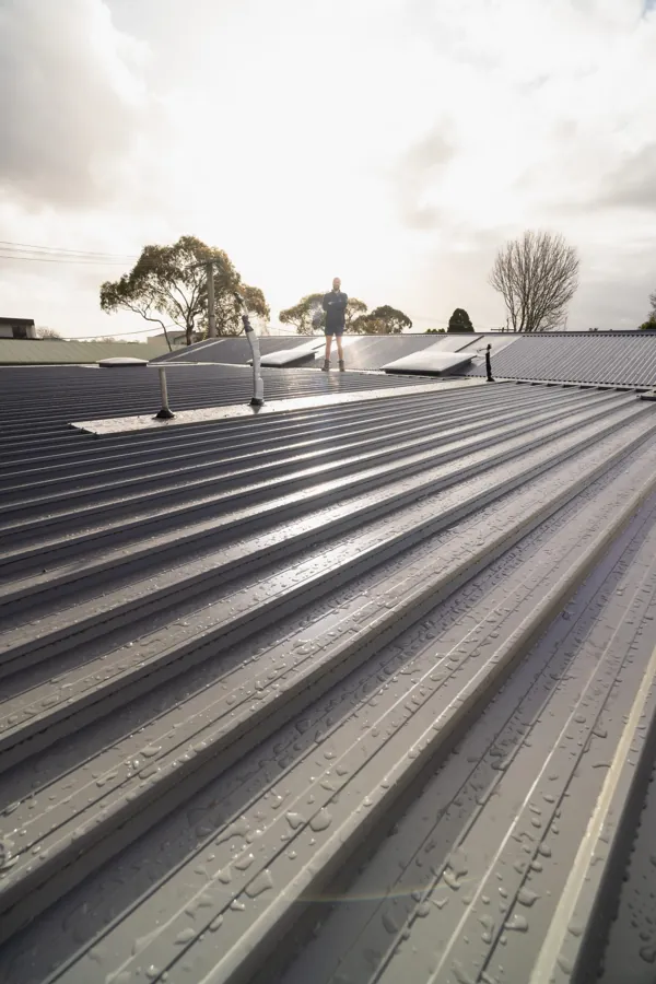 New metal roof at sunset with a roof plumber on the ridge